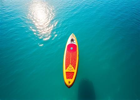 Stand-up paddleboard floating on crystal clear lake water under a sunny sky